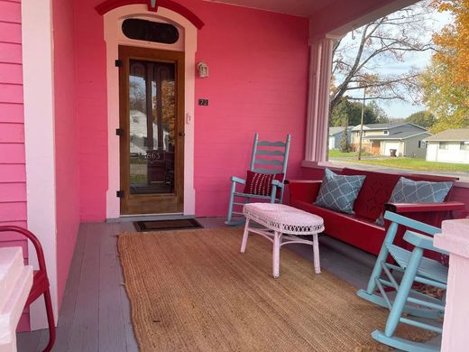 A pink porch with a couch and rocking chairs