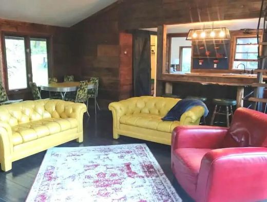 A living room with yellow couches and red chairs