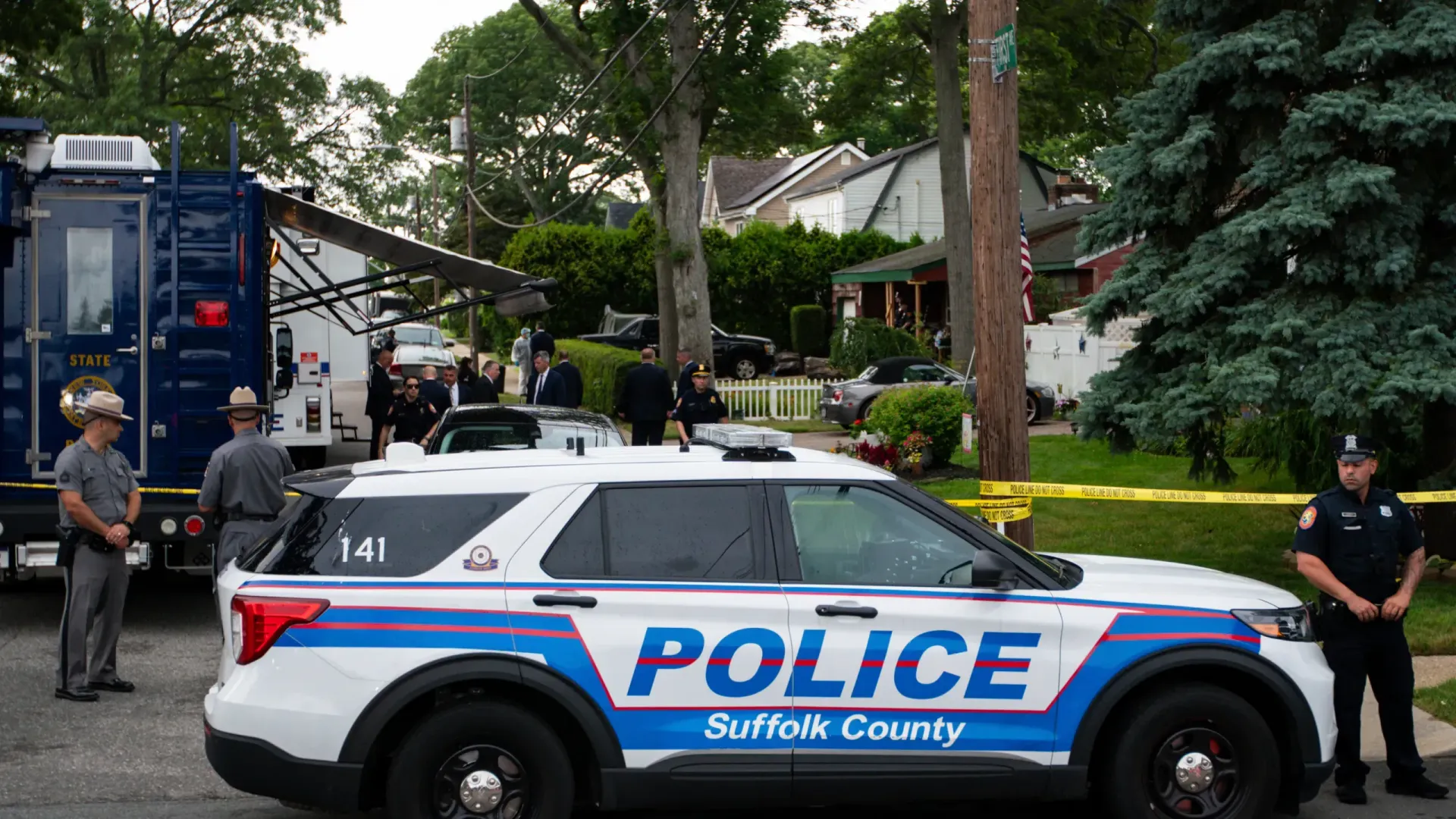 A blue and white police car is parked in front of a house.