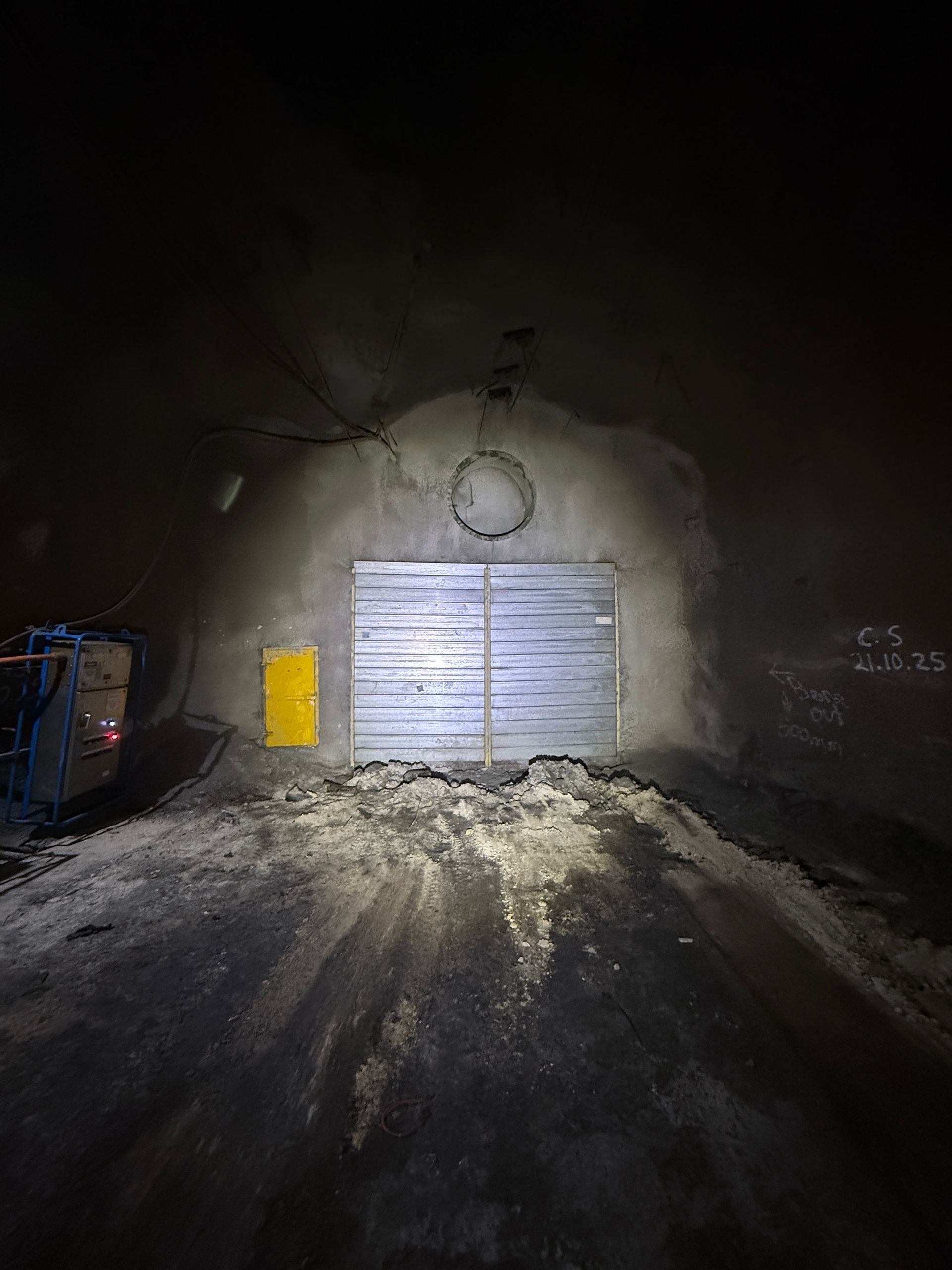 Dim tunnel entrance with a metal double door, lit by headlights on a snowy road at night — Vent Doors Australia in Ryan, QLD