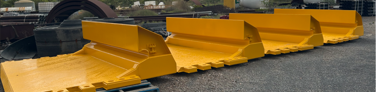 Yellow metal barriers lined up on asphalt, viewed from the side.
