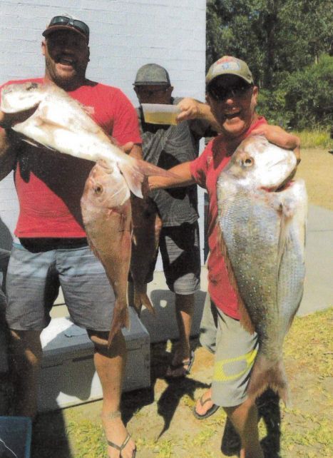 A Man In A Red Shirt Is Holding A Large Fish — Pacific Palms Bowling Club In Smiths Lake, NSW
