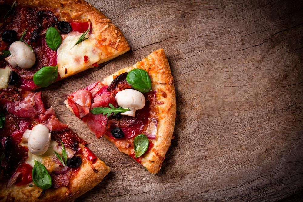 A Pizza With A Slice Missing Is On A Wooden Table — Pacific Palms Bowling Club In Smiths Lake, NSW