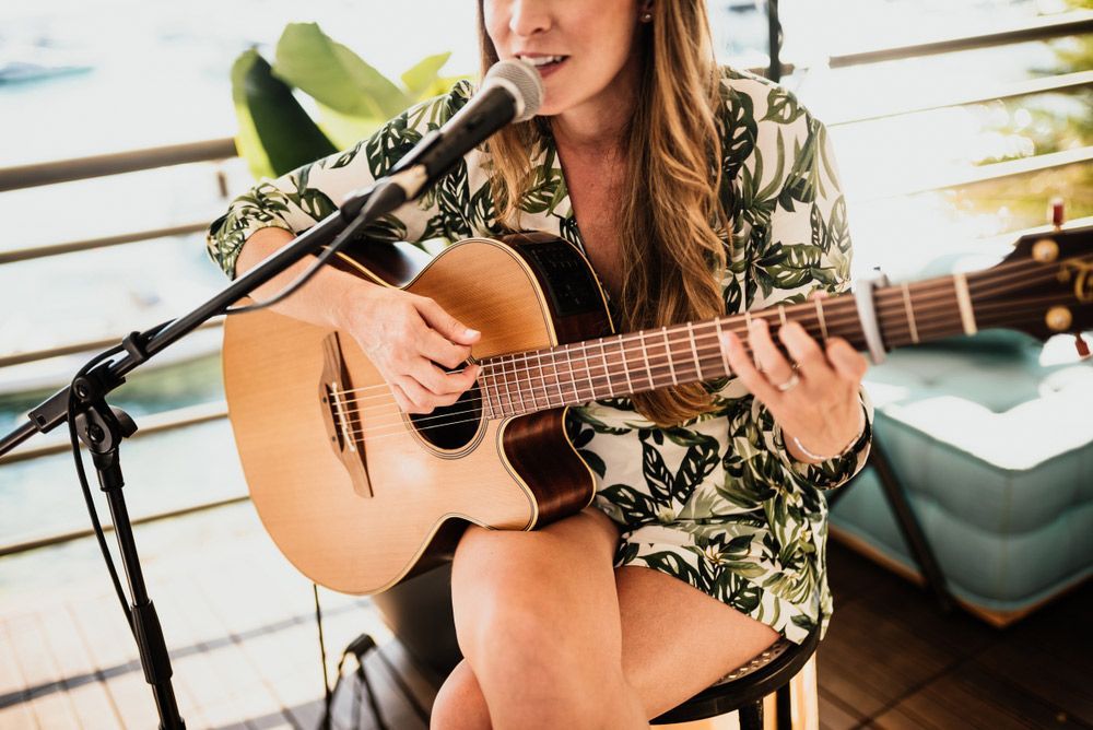 A Woman Is Playing A Guitar And Singing Into A Microphone — Pacific Palms Bowling Club In Smiths Lake, NSW