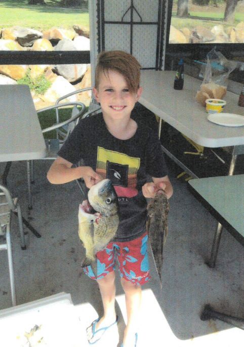 A Young Boy Is Holding A Large Fish In His Hands — Pacific Palms Bowling Club In Smiths Lake, NSW