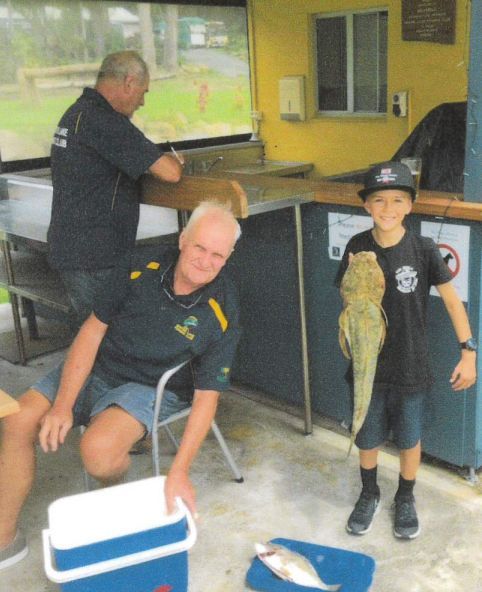 A Boy Holding A Fish Next To A Man Holding A Cooler — Pacific Palms Bowling Club In Smiths Lake, NSW