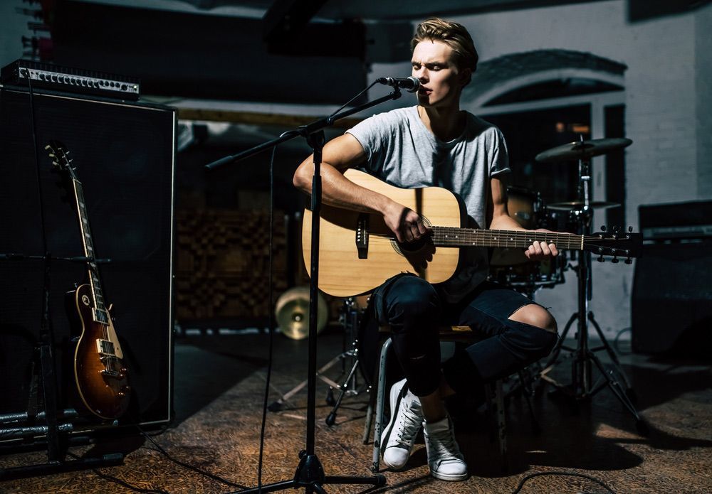 A Man Is Playing An Acoustic Guitar In Front Of A Microphone — Pacific Palms Bowling Club In Smiths Lake, NSW