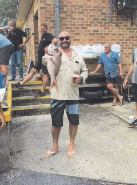 A Man Holding A Large Fish In Front Of A Brick Building — Pacific Palms Bowling Club In Smiths Lake, NSW