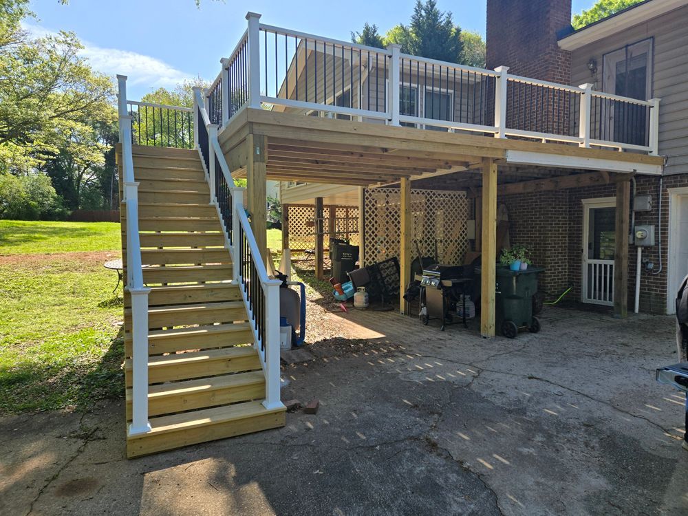 Wooden deck with stairs attached to a house. Underneath are lattice walls, storage, and a grill.