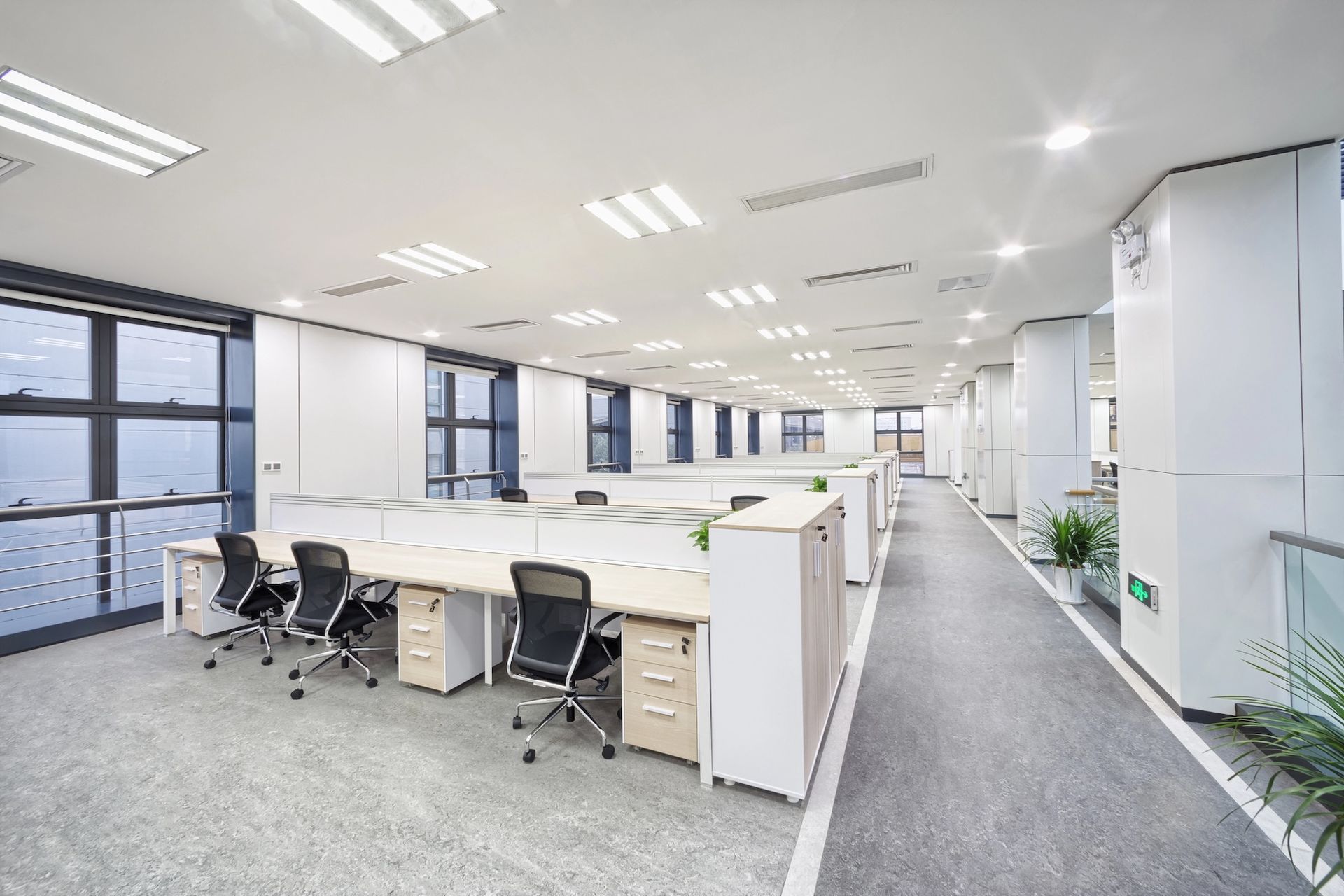Office cubicles with desks and chairs in a modern, bright space.