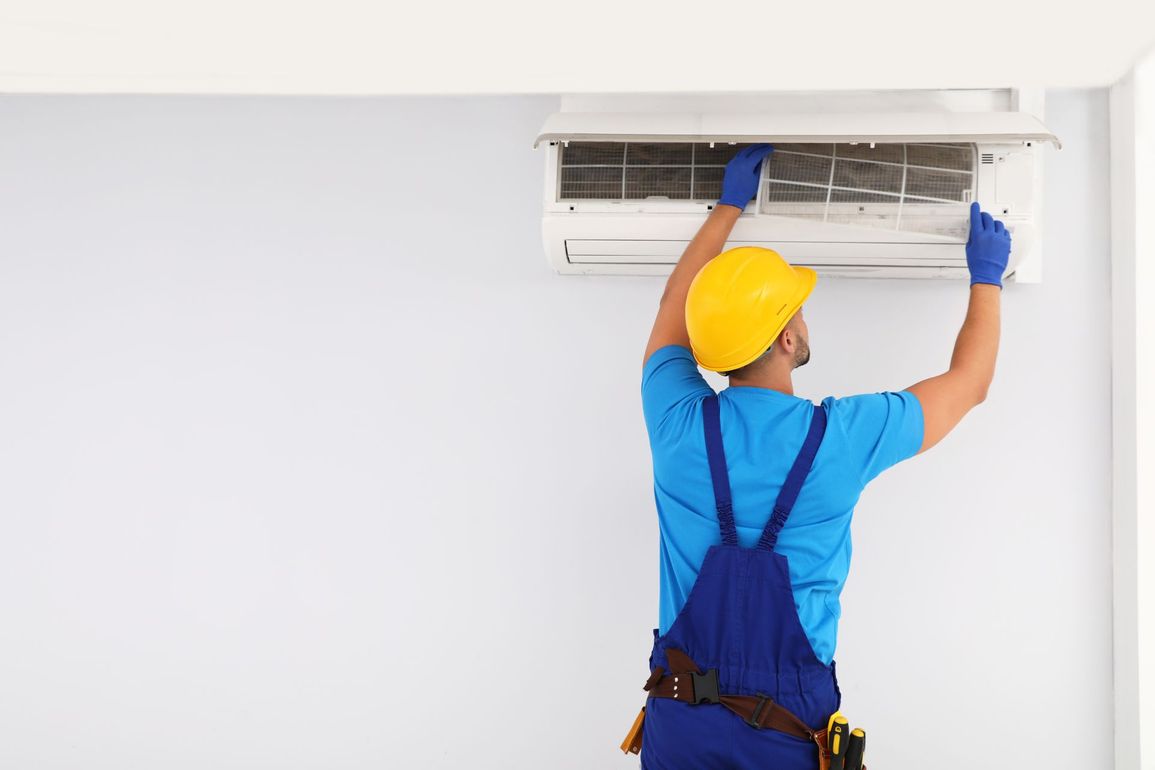 A man is working on an air conditioner in a room.