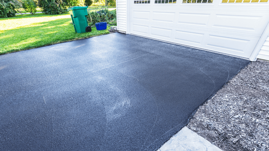 Smooth newly paved asphalt driveway in front of a residential garage with clean edges during an asphalt paving service in Highlands Ranch, CO