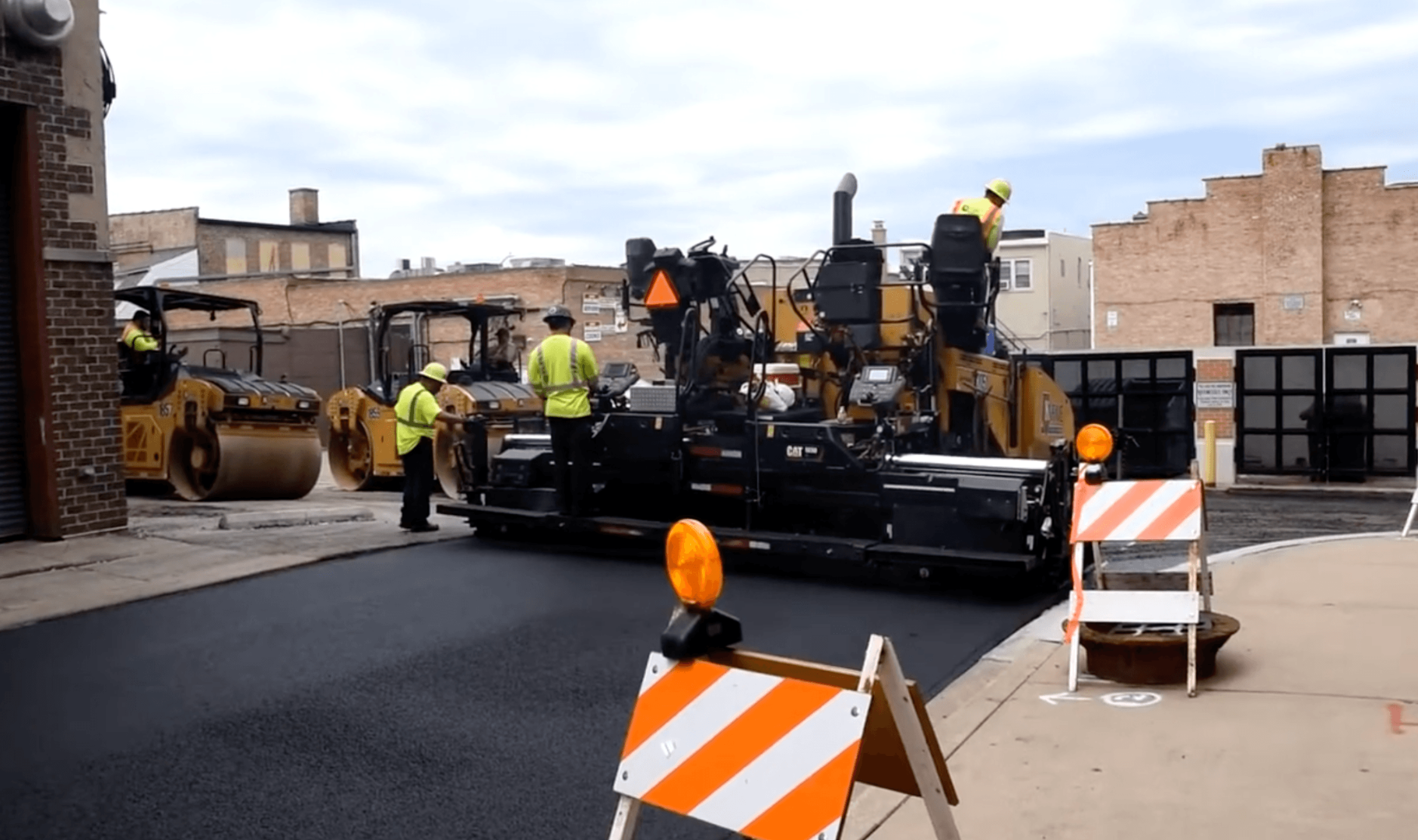 Large paving machine laying a smooth layer of asphalt on a city street while workers monitor progress during an asphalt paving service in Highlands Ranch, CO