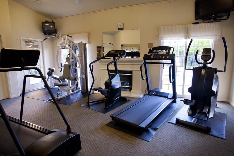 Gym with multiple exercise machines, including treadmills and a weight machine.