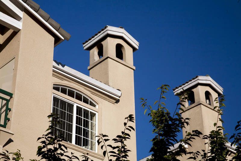Tan stucco building with chimneys against a clear blue sky.