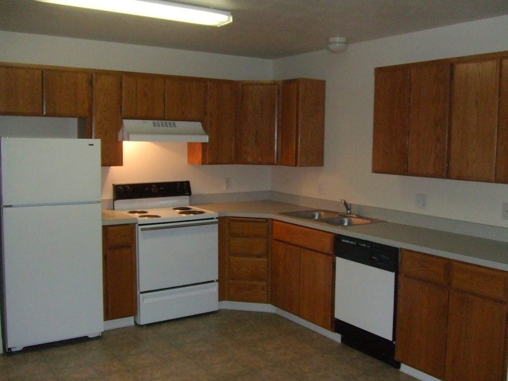 Kitchen with white appliances, brown cabinets, and a gray countertop.