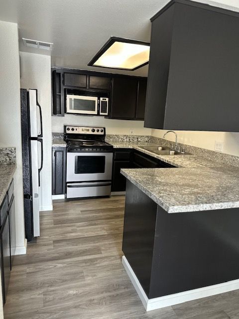 Kitchen with dark gray cabinets, stainless steel appliances, and gray countertops.