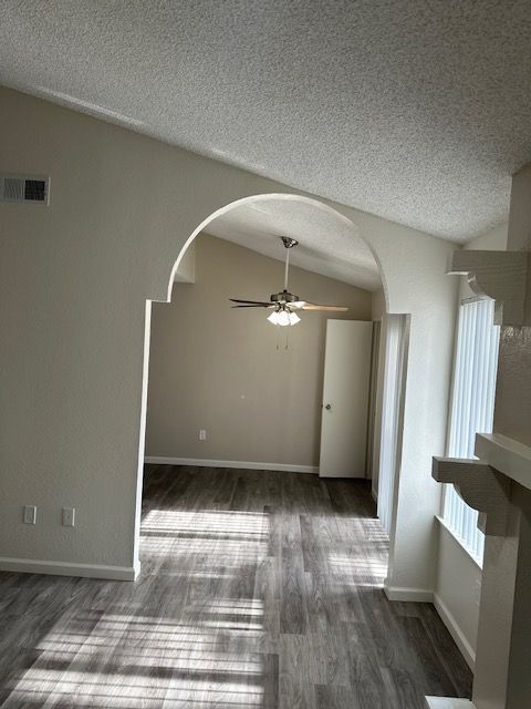 Interior view of a room with an archway, hardwood floors, and a ceiling fan.