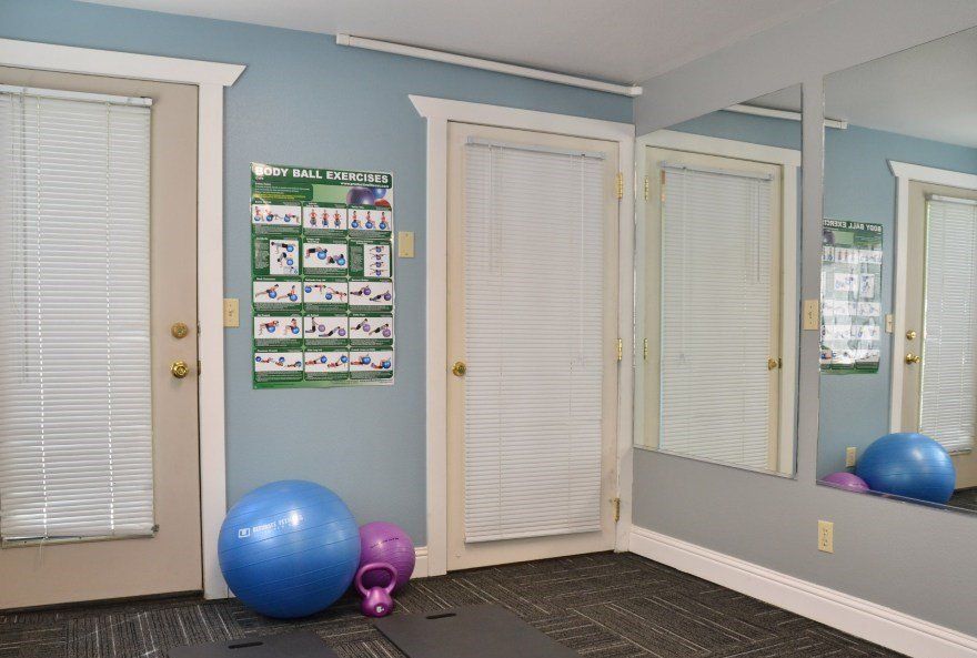 Gym area with blue walls, exercise balls, mirror, and workout chart.
