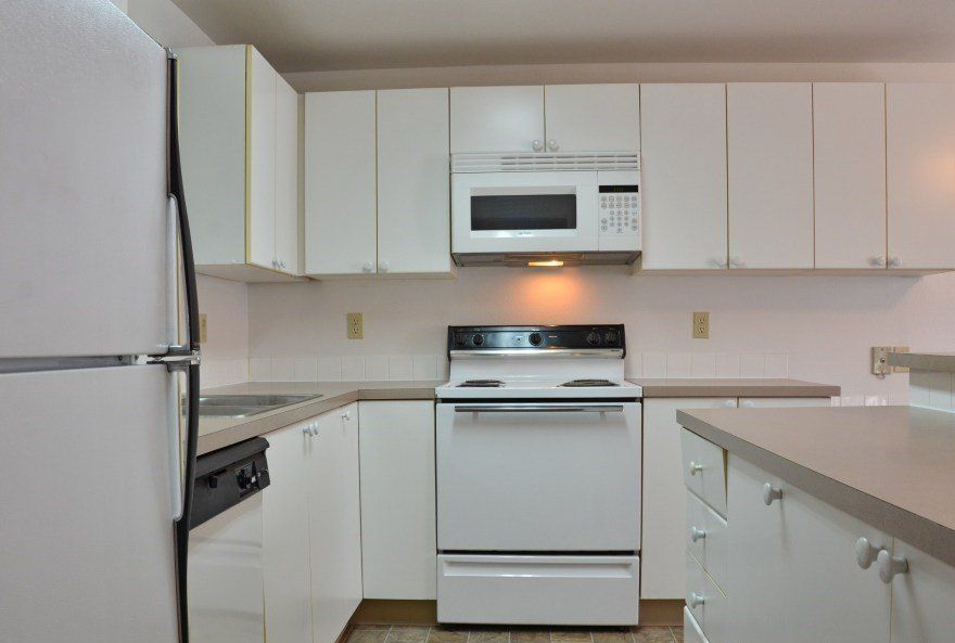 White kitchen with white cabinets, appliances, and countertops.