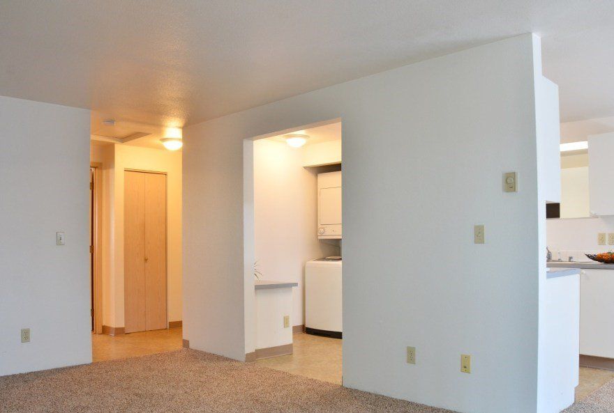 Interior view of an apartment, showing hallways, doorways, carpet, and white walls.