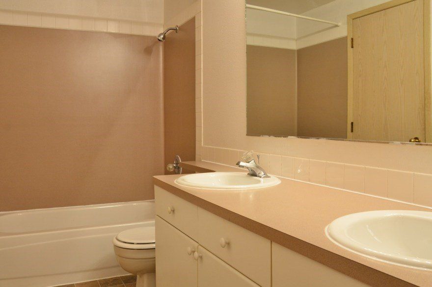 Bathroom with a beige color scheme, featuring a bathtub, sink vanity, and mirror.