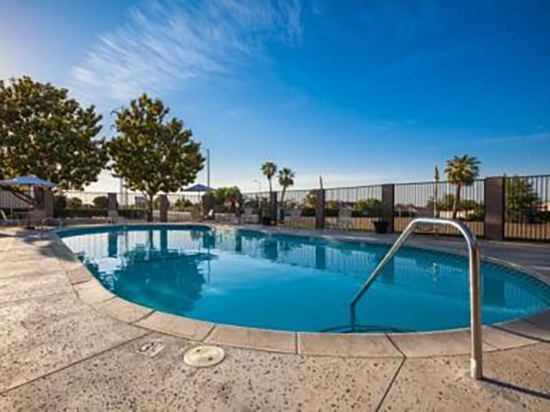 Pool with blue water and surrounding concrete under a bright blue sky.
