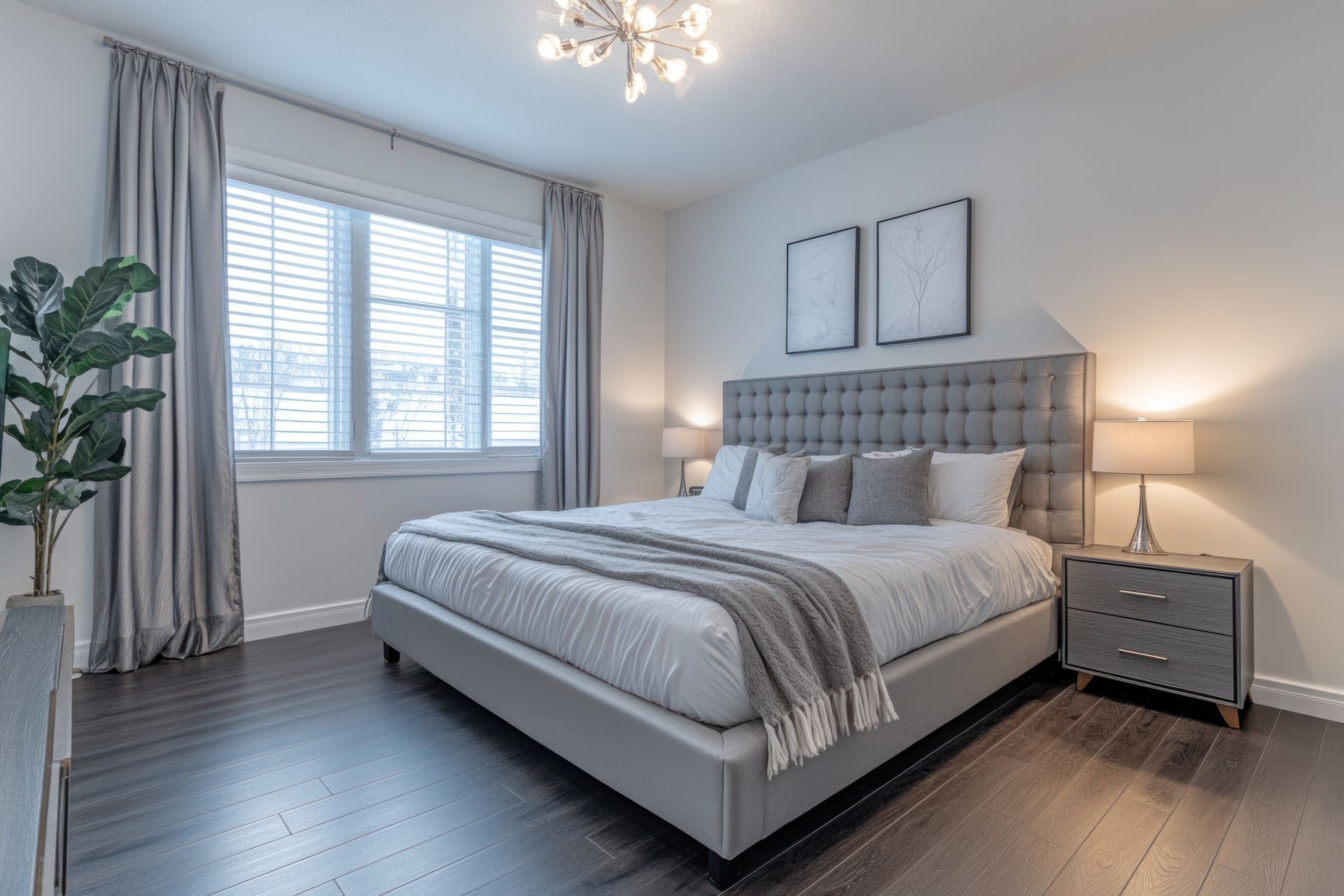 Bedroom with gray bed, nightstand, and curtains; large window with blinds.