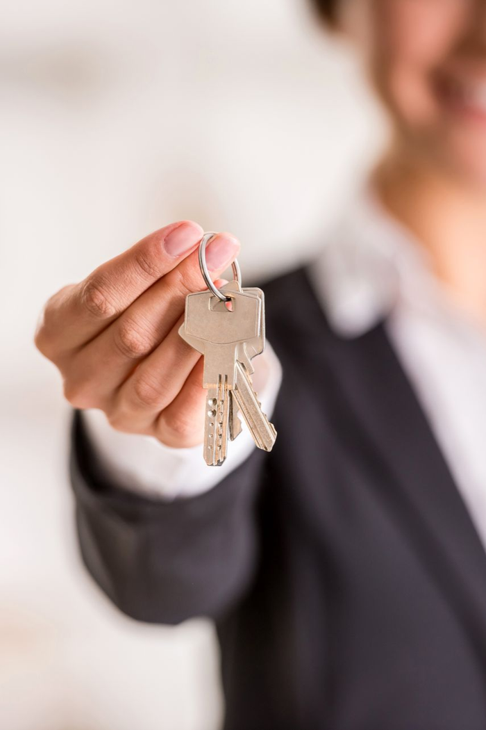 Woman in blazer holding up a set of keys, smiling.