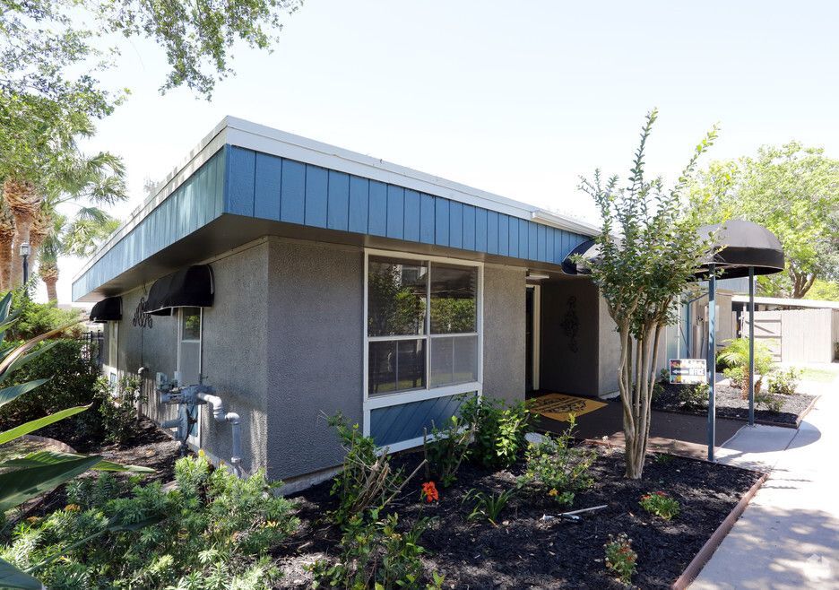 Exterior of a one-story building with a blue awning and landscaping.