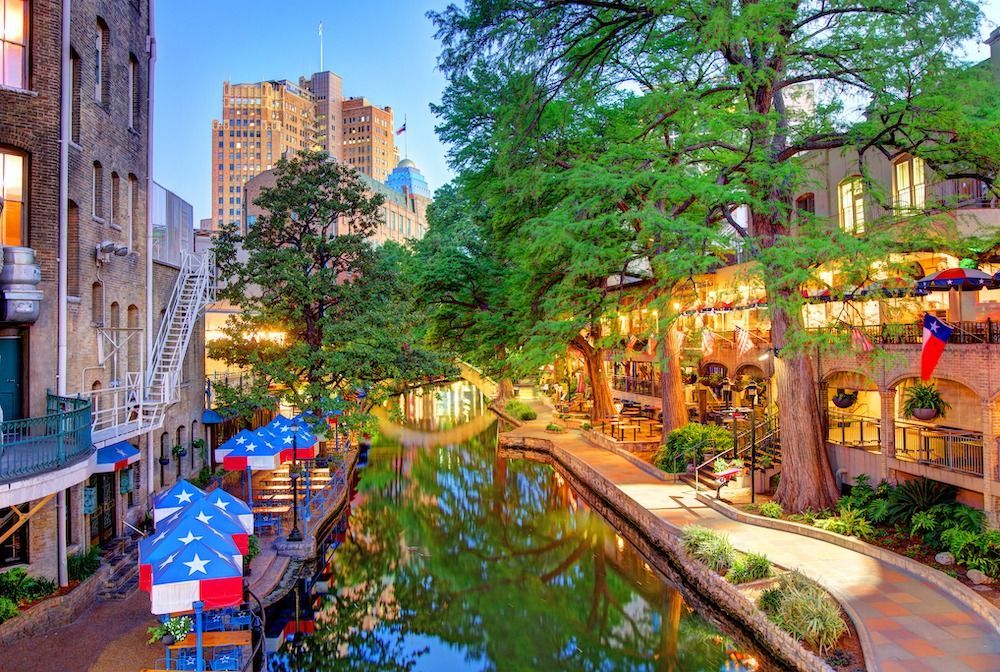 Riverwalk in San Antonio, Texas, with restaurants, trees, and buildings lining the water's edge.