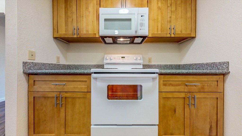 Kitchen with wooden cabinets, white appliances, and a microwave above the stove.