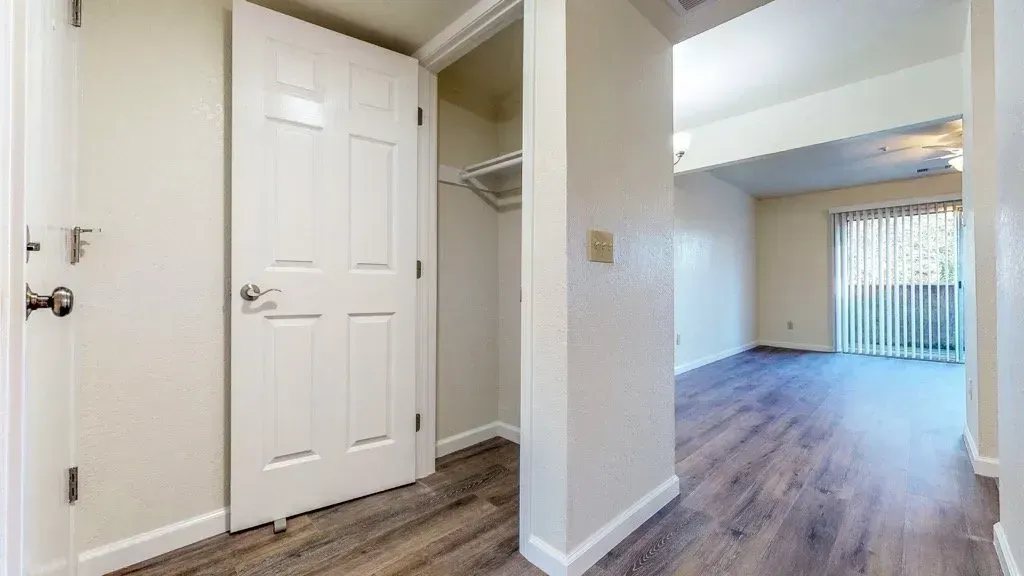 Interior view: Entryway with closet, leading to living area with sliding glass door.