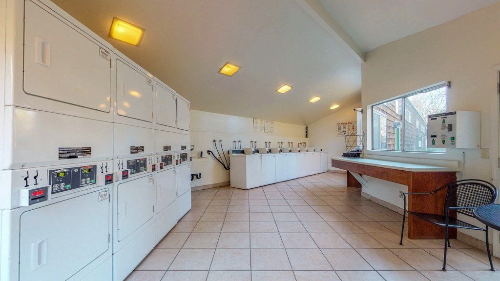 Laundry room with white appliances, tiled floor, and small windows.