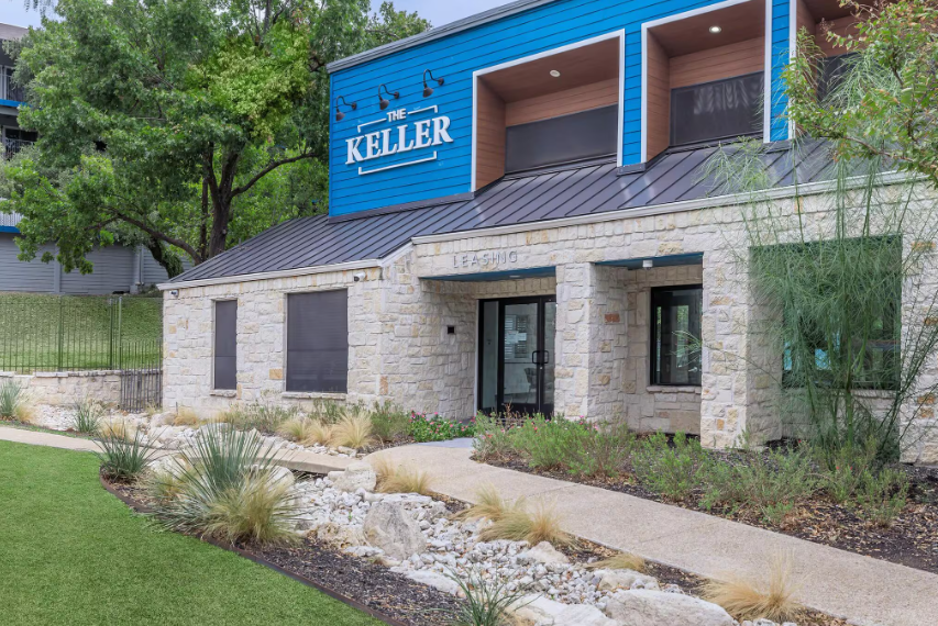 Keller apartment complex entrance with blue facade, light stone, and landscaping.