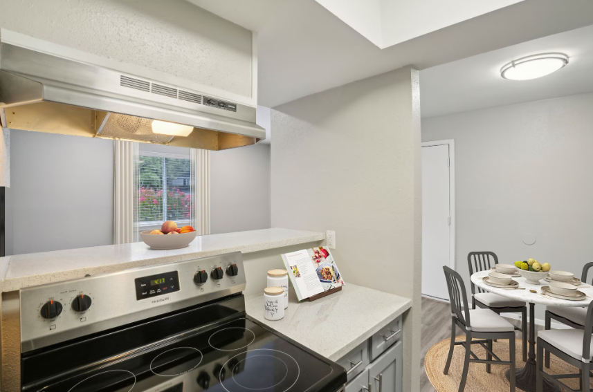 Kitchen with stainless steel appliances, breakfast bar, and a dining area with a round table.