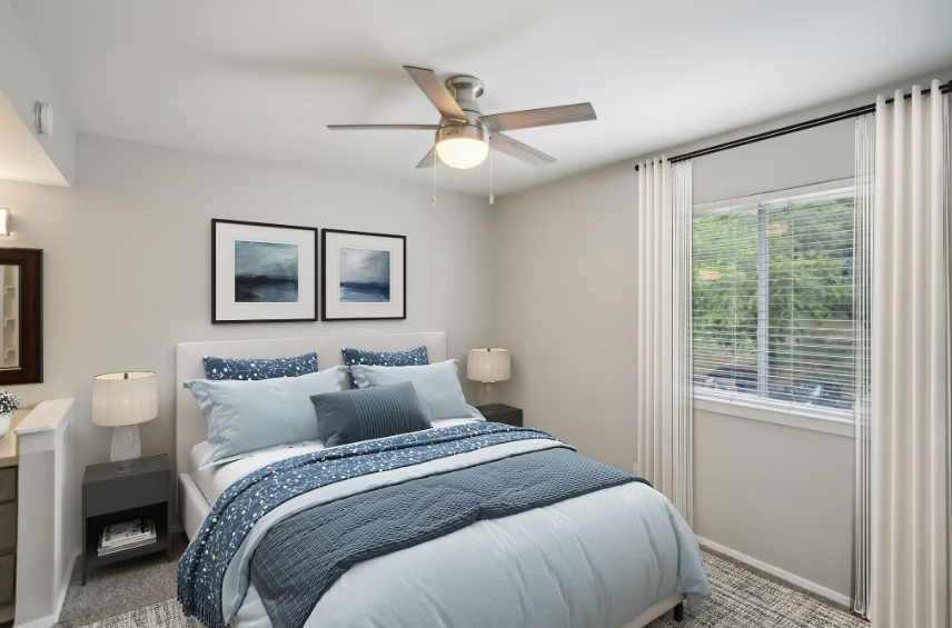 Bedroom with bed, nightstands, window, and ceiling fan. Blue and white bedding.