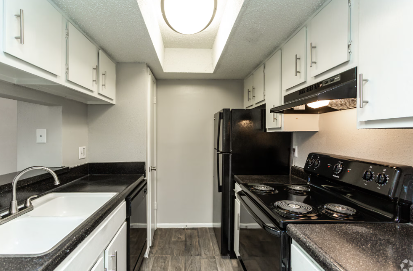 Kitchen with white cabinets, black appliances, and countertops; gray walls; overhead lighting.