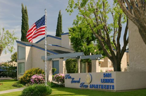Bedroom with gray bed, nightstand, and curtains; large window with blinds.