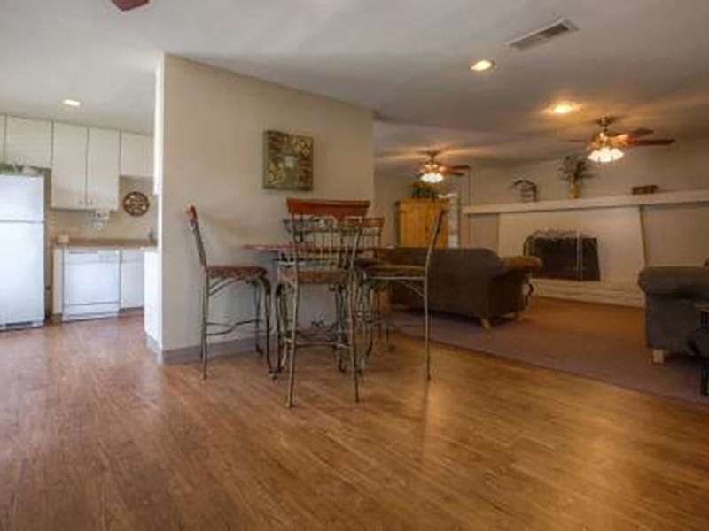 Interior with hardwood floors, kitchen, dining table, and living room with fireplace.
