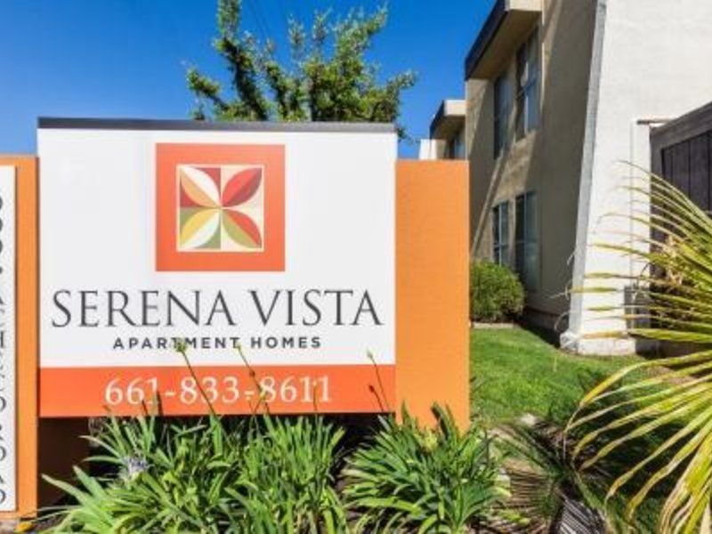 Serena Vista Apartments sign with logo and phone number, set in a sunny, residential area.