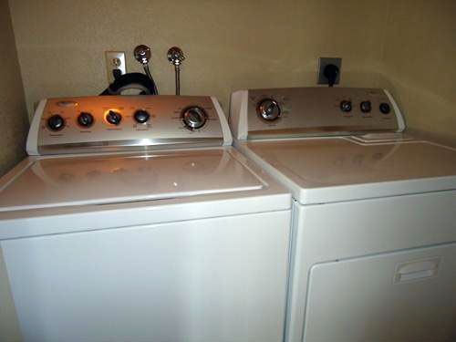 White washer and dryer appliances in a laundry room, with knobs and power outlets visible.