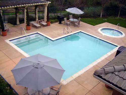 Pool area with swimming pool, hot tub, patio furniture, and umbrellas.
