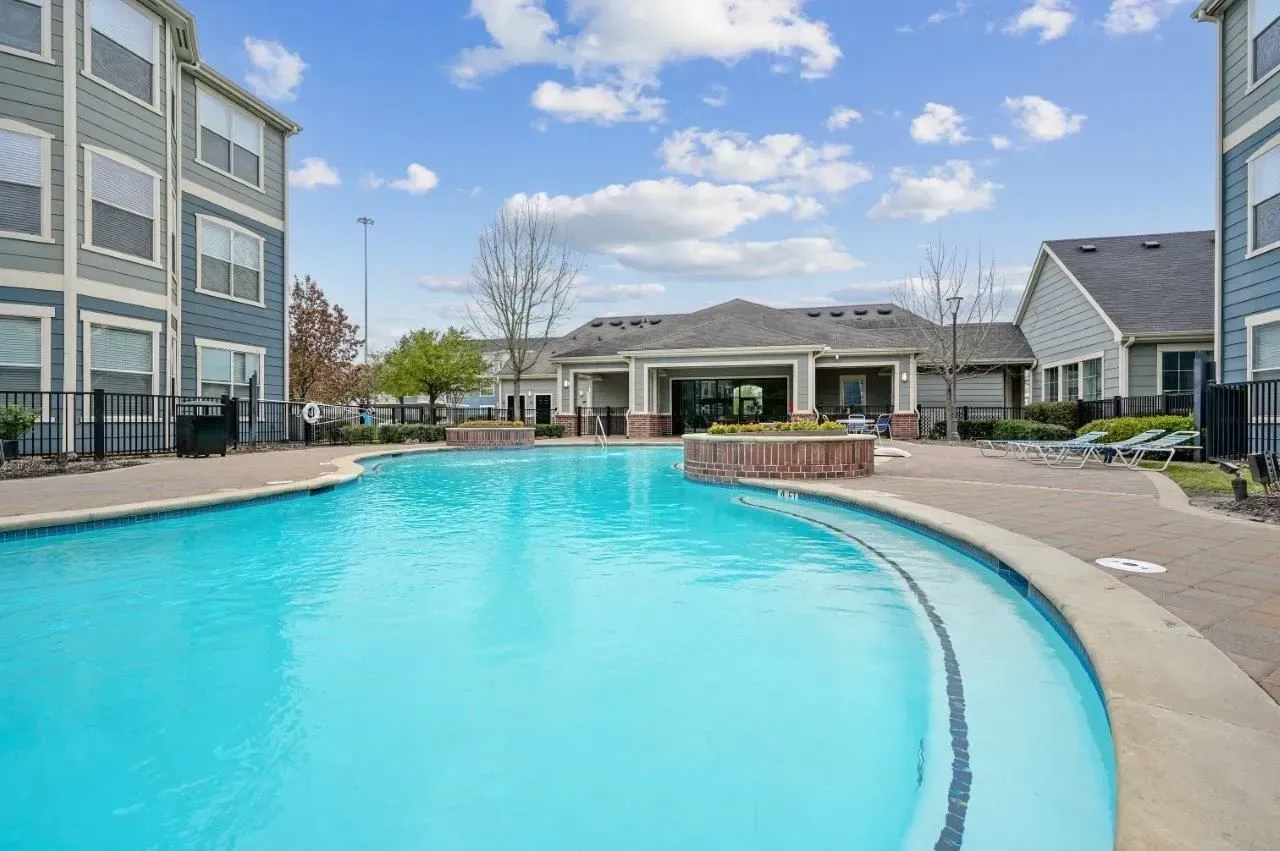 Bedroom with a bed, nightstand, lamp, decorative pillows, and round mirror.