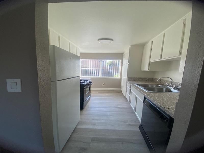 Kitchen with white cabinets, appliances, and light gray flooring.