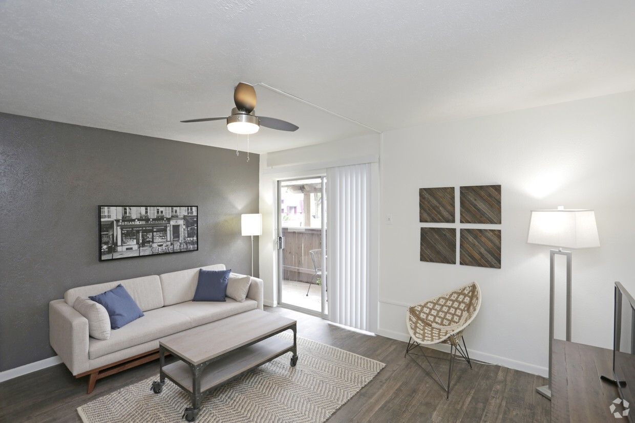 Living room with sofa, coffee table, sliding door to balcony, hardwood floors, and decor.