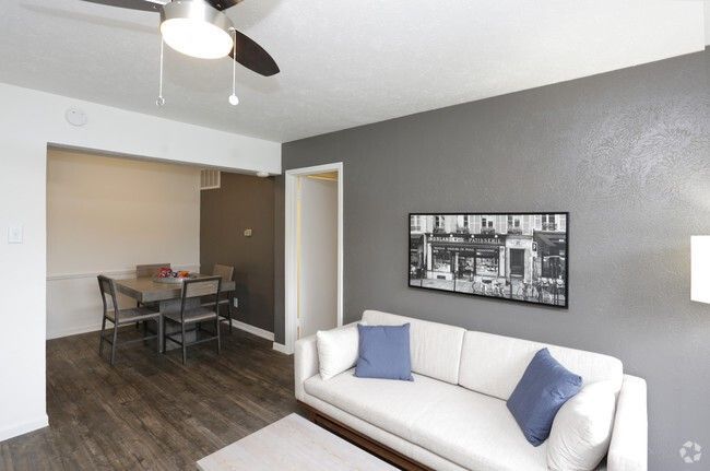 Living room with a white couch, gray walls, dining area, and dark wood floor.