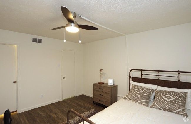 Bedroom with bed, nightstand, ceiling fan, and closed door.