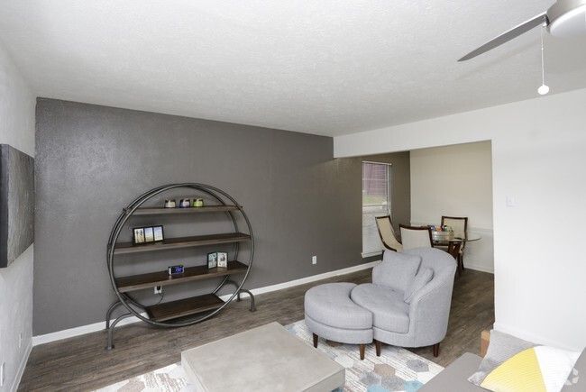 Living room with gray walls, shelving unit, gray armchair, and dining area.