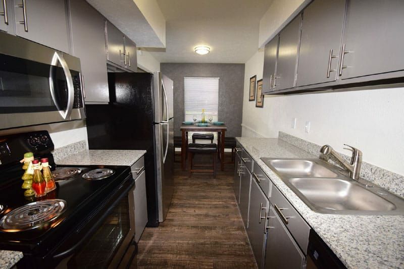 Kitchen with gray cabinets, stainless steel appliances, granite countertops, and a dining area.
